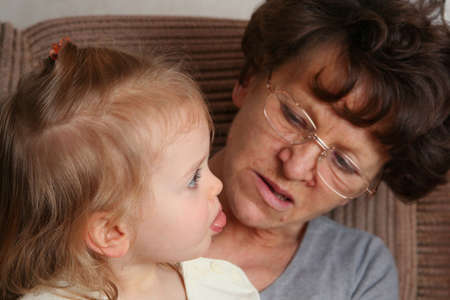 Grandmother sitting on the armchair with her grandchildren
