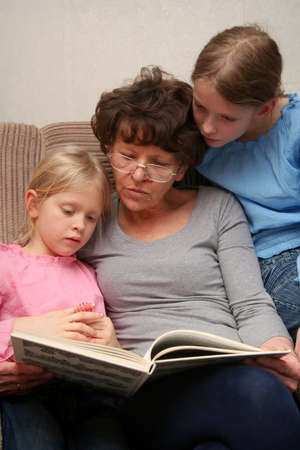 Grandmother sitting on the armchair with her grandchildren and reading