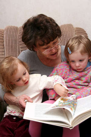 Grandmother sitting on the armchair with her grandchildren and reading