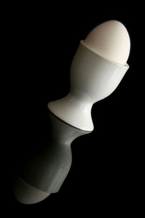 White egg in a cup on a black background