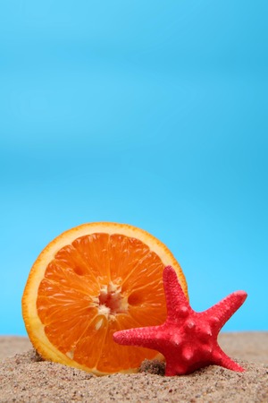 Juicy orange on sand on a blue backgroundの写真素材
