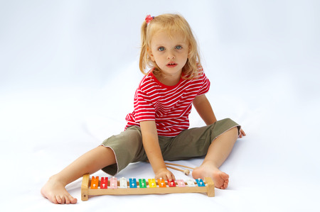 Little girl wearing striped red t-shirt playing the rainbow xylophoneの写真素材