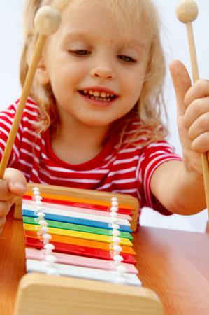 Little girl wearing striped red t-shirt playing the rainbow xylophoneの写真素材