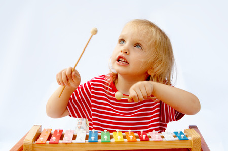 Little girl wearing striped red t-shirt playing the rainbow xylophoneの写真素材