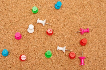 Colorful pins on a brown corkboard