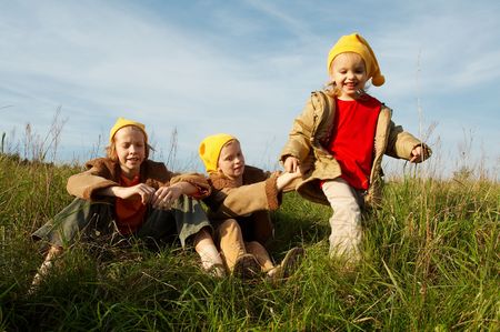 Children wearing yellow caps  playing on autumnal meadowの写真素材