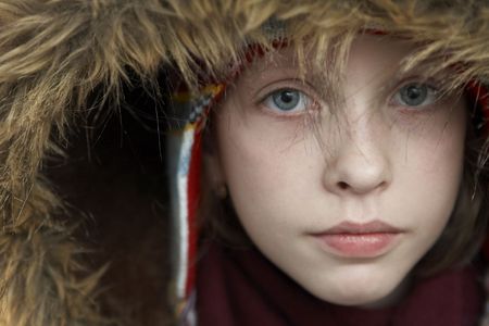Young girl wearing woolen cap, scarf and gloves on blue 