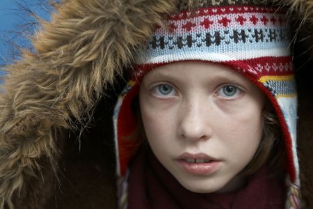 Young girl wearing woolen cap, scarf and gloves on blue 
