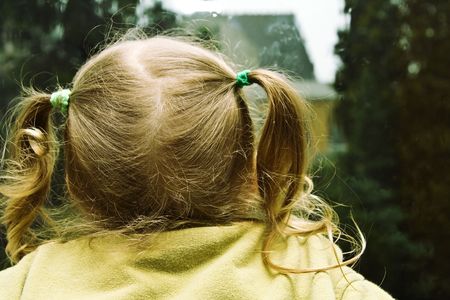 Little girl sitting near the window in the rainy dayの写真素材