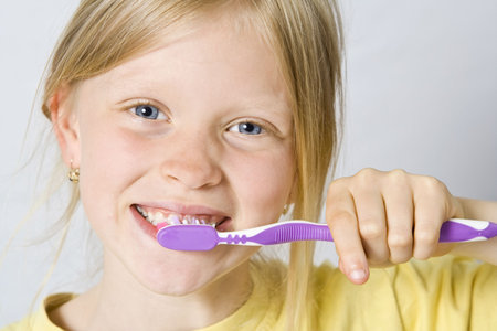 Little girl wearing colorful t-shirts brushing teethの写真素材