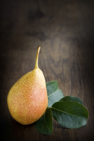 Yellow pear lying on a dark brown table.の写真素材
