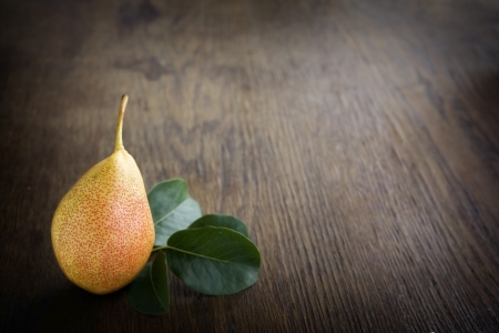 Yellow pear lying on a dark brown table の写真素材