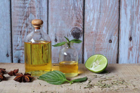 aroma massage oil bottle on the wooden table with slice of lemon lime and basil leave in the kitchen...