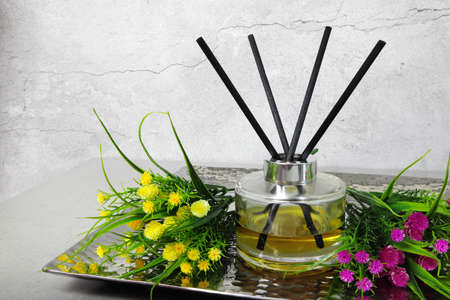 luxury glass bottle of aromatic scent reed diffuser with black sticks put in the stainless plate on the grey table in the bed roomの写真素材