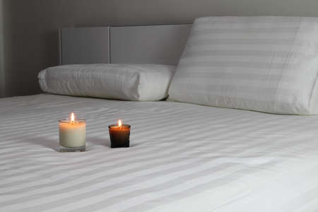 aromatic scent candles are lighting on the white bed in a bedroom