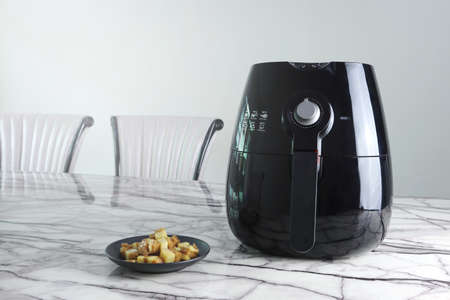 a black air fryer or oil free fryer appliance is on the marble dinning table in the dinning room...