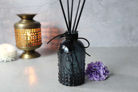 luxury aromatic scented reed sticks diffuser glass bottle is on the grey table with pupple flower...