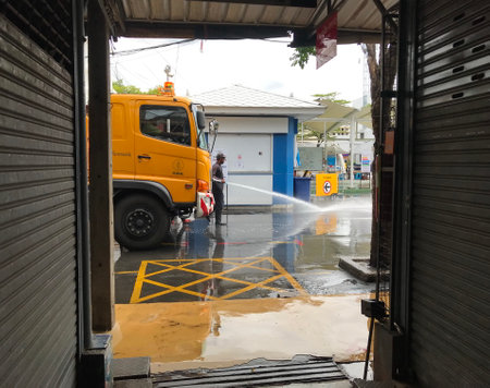 The yellow water truck of the market department is cleaning the street in the Chatuchak weekend market to reduce the infection chanceのeditorial素材