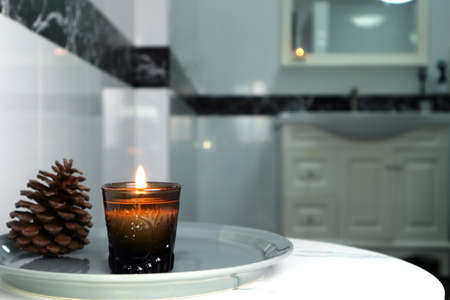 aromatic scented candle glass is put on the white marble table in a luxury white bathroom toilet to creat relax and cozy and clean ambient in resort hotel spa christ mas valentineの写真素材