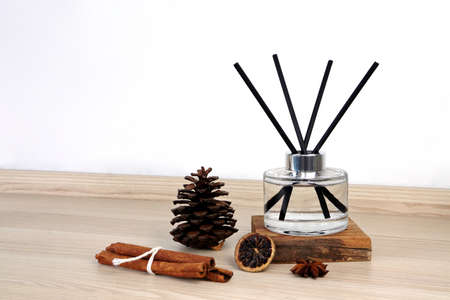 luxury aroma scent reed diffuser glass bottle is on the wooden table and pinecone, cinnamon sticks, anise to creat romantic and relax ambient in the bedroom white cement wall on happy valentine dayの写真素材