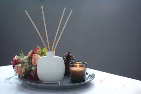 luxury aroma scent reed diffuser ceramic vase is on white marble table with glass of scented candle...