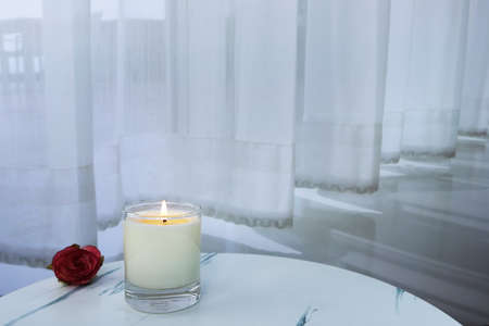 The luxury lighting aromatic scented glass candle diplay on the white marble table in the white bedroom with background of the curtain to creat romantic and relax ambient on Valentine dayの写真素材