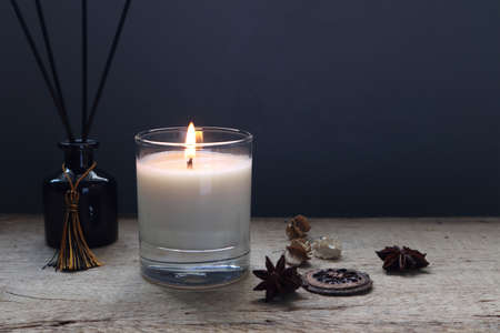 the burning luxury aromatic scented candle glass on the wooden table with background of vintage...
