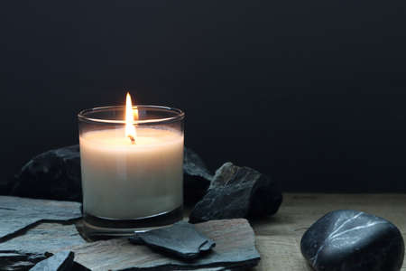 the burning luxury aromatic scented candle glass on the wooden table with background of vintage wooden wall of the cottage in the living room to creat relax ambient during christmas party celebrationの写真素材