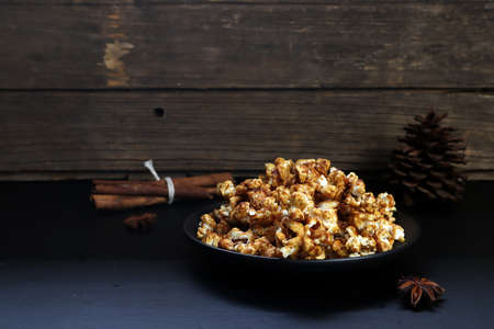 a dish of homemade caramel popcorn is on the black table with background of wooden wall in the...
