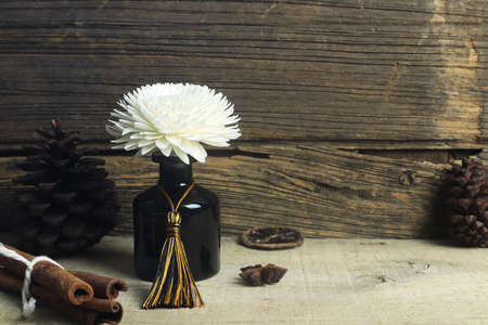 nice aromatic scented reed diffuser air freshener bottle on wooden table with pine cone and...