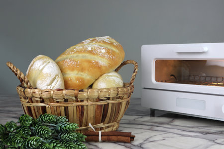 a basket of delicious homemade toast breads are on the white marble table with toaster oven,...