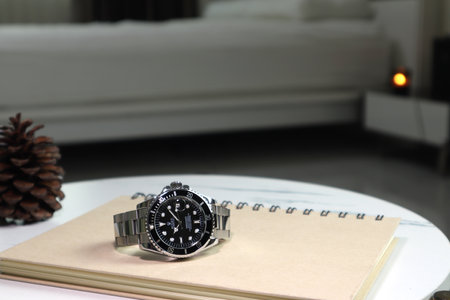 The Rolex vintage wristwatch ceramic bezel model black oyster perpetual submariner date 39 mm display on white marble table with a notebook and tablet on background of white bed roomのeditorial素材
