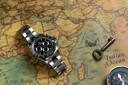 Rolex wristwatch model cosmograph daytona oyster perpetual superlative chronometer with black ceramic bezel stainless steel body is displayed on the world map with old ancient keyのeditorial素材