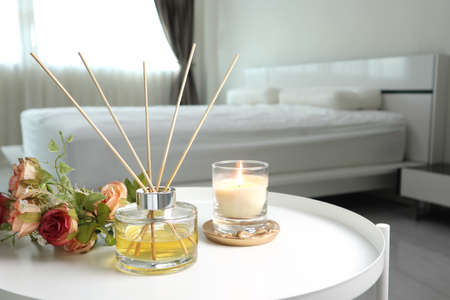 luxury aromatic scent of reed diffuser glass bottle is used as room freshener on white metal table with candle in bedroom to creat relax and romantic ambient with background of nicの写真素材