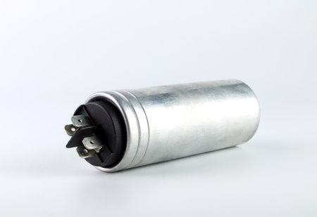 an old model of start capacitor or run capacitor is on the white table after be changed during the fixing process of an old air conditionの写真素材