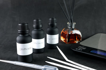 black essential oil bottl is on black table with blotting paper , fragrance bottle and digital scale are used to blend the nice scent for making perfume and reed diffuser by perfumの写真素材