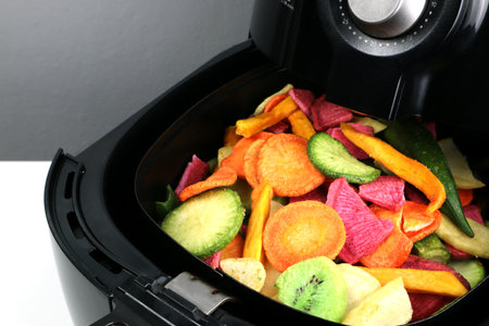 homemade fried dried vegetables and fruits such as carrot, potato, kiwi, roselle are cooked by using a black air fryer or oil free fryer appliance for being lunch in afternoon withの写真素材