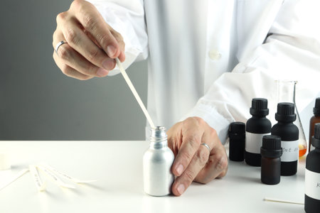 essential oil bottle , chemical beaker are on white table with blotting papers , fragrance bottle are used to blend nice scent for making perfume and candle by perfumer in laboratoの写真素材