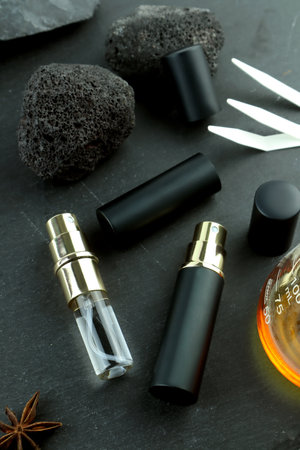 The black spray aroma body perfume bottles put on black stone table with stones , blotter papers ,...