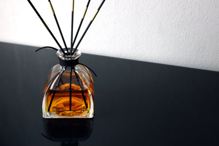 luxury aroma scent reed diffuser glass bottle is on glass table and white cement wall background in...
