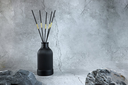 luxury aroma scent reed diffuser glass bottle is on crack stone table to create romantic and relax ambient in bedroom with grey cracked cement wall background in the morning of hapの写真素材