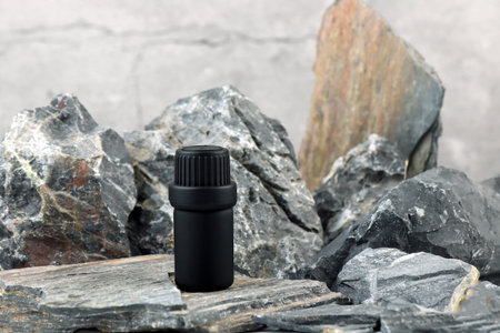 black color essential oil bottle on stone table with stones and rocks in luxury spa for create nice smell scent ambient in massage room for customer to relax fresh cozy feeling witの写真素材