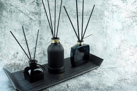 aroma scent reed diffuser glass bottle are on grey stone table with essential oil bottle and wood tray to creat romantic and relax ambient with background of nice grey curtaの写真素材