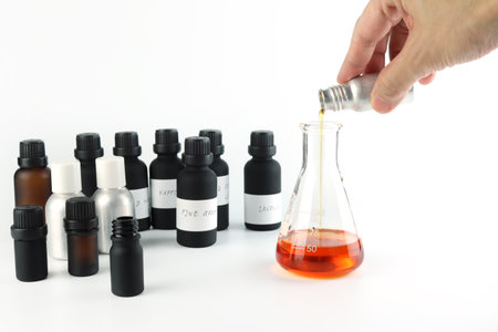 chemical beaker , flask is on white table with blotting paper , fragrance bottle and essential oil bottle are used to blend the nice scent for making perfume and candle by perfumerの写真素材