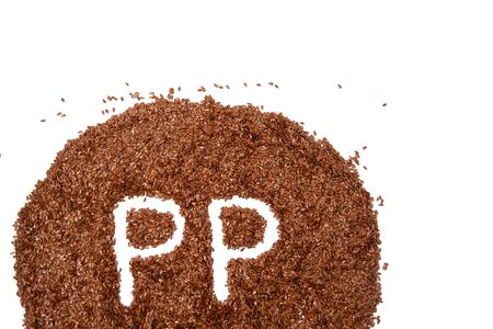 heap of brown flax seeds isolated on white background a white letter of vitamin PPの写真素材