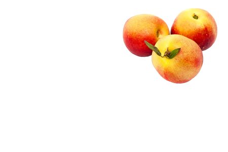 three ripe yellow and red nectarines with green leaves isolated on a white backgroundの写真素材