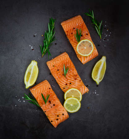 Salmon fillet steaks with lemon and herbs on a black backgroundの写真素材