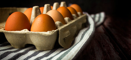 Fresh eggs in a box on a wooden background. Copy space