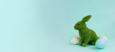 Decorative green rabbit and Easter eggs on a blue background, copy space.の写真素材