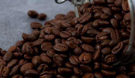 Roasted coffee beans scattered on a dark stone background.